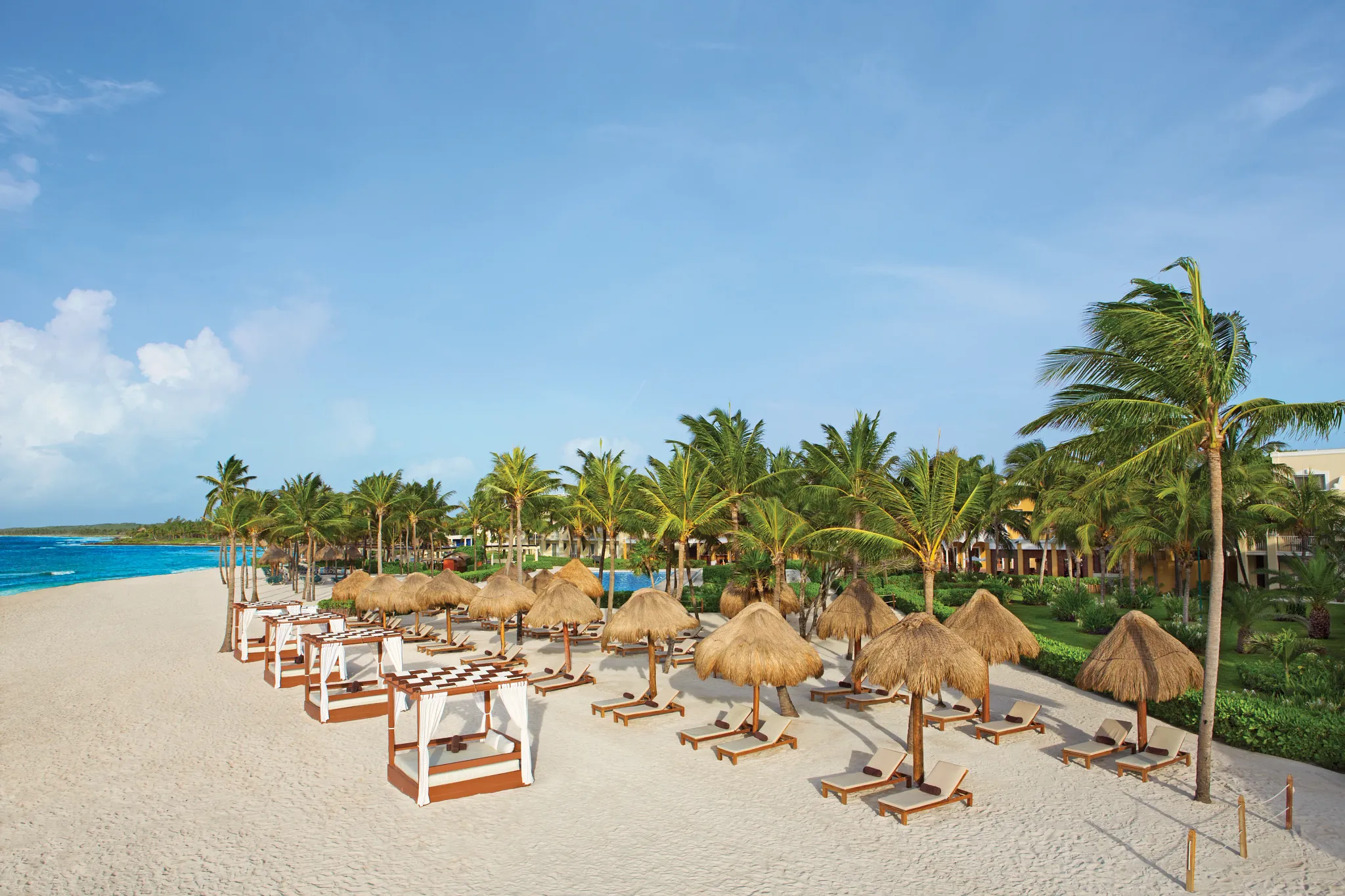 Beach cabanas and palapa umbrellas along the white-sand beach at Dreams Tulum Resort & Spa.