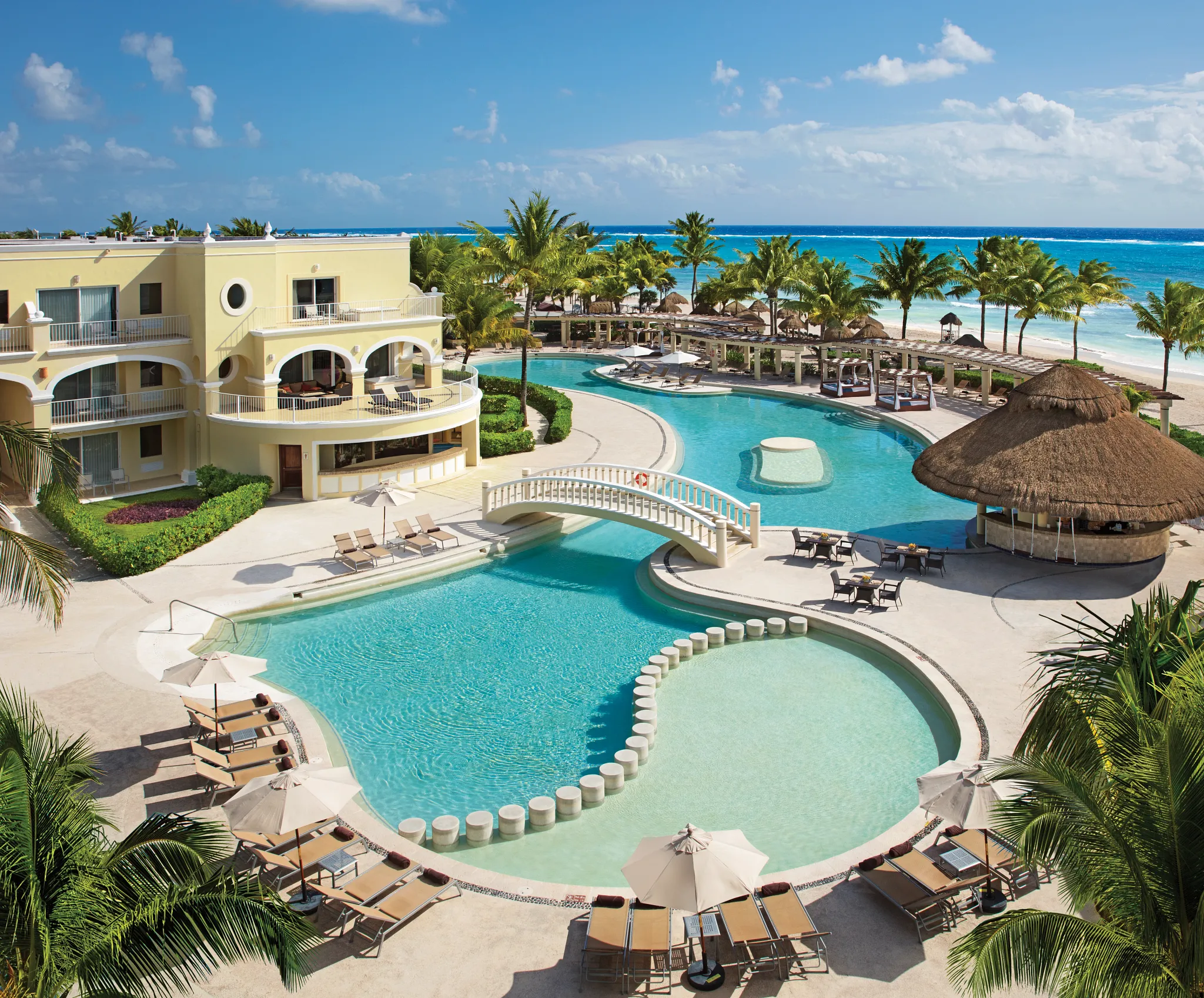 Expansive beachfront pool surrounded by palm trees at Dreams Tulum Resort & Spa in Riviera Maya.