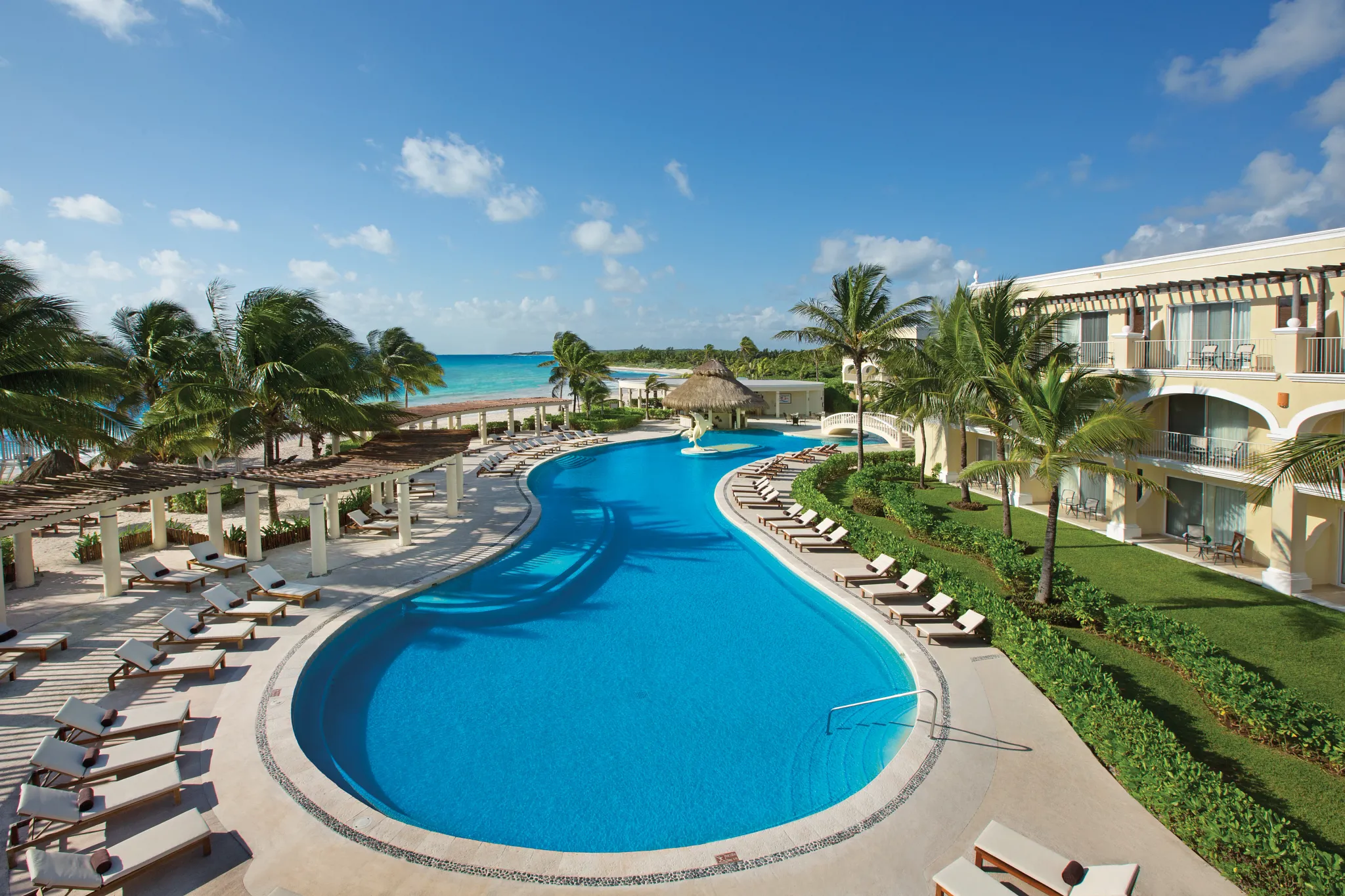 Large resort pool surrounded by palm trees and lounge chairs at Dreams Tulum Resort & Spa.