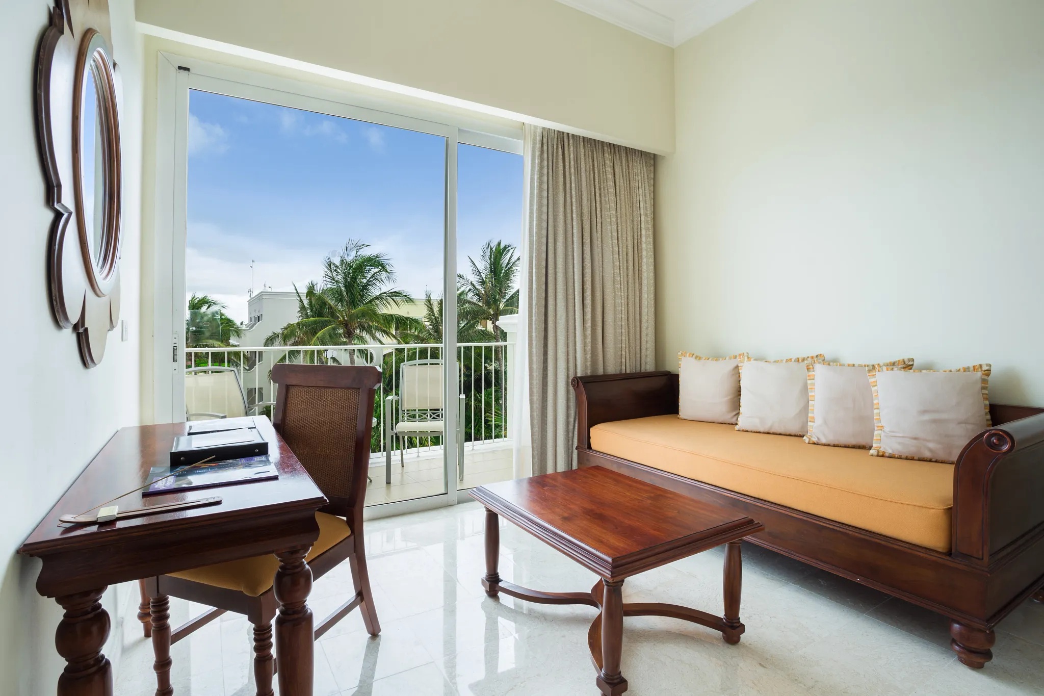 Junior Suite Garden View living area with sofa, desk, and private balcony at Dreams Tulum Resort & Spa.