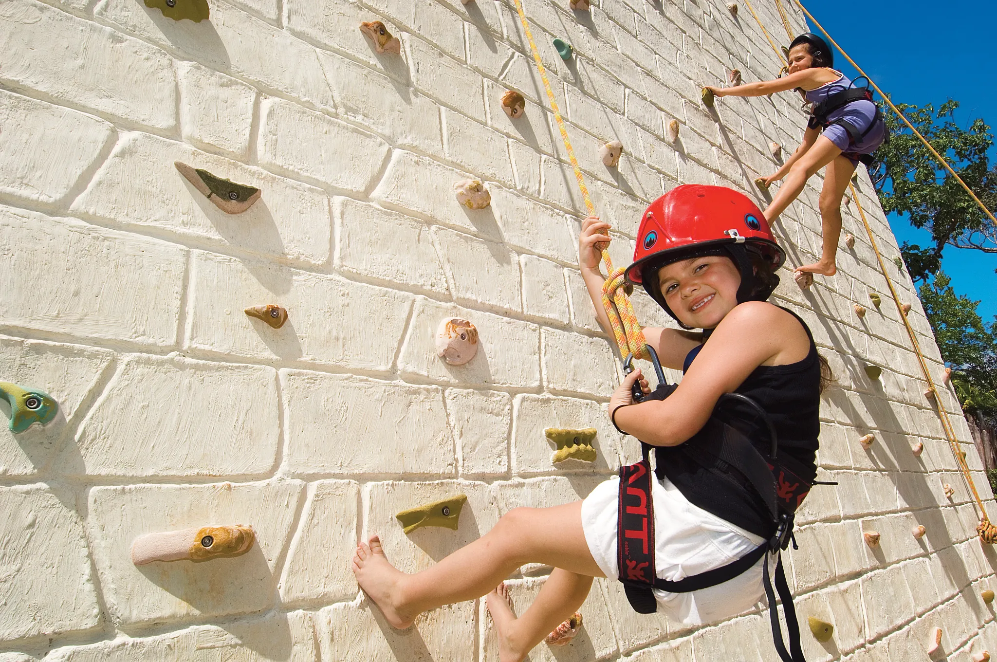 Children climbing an outdoor rock wall at Dreams Tulum Resort & Spa’s family activity center.
