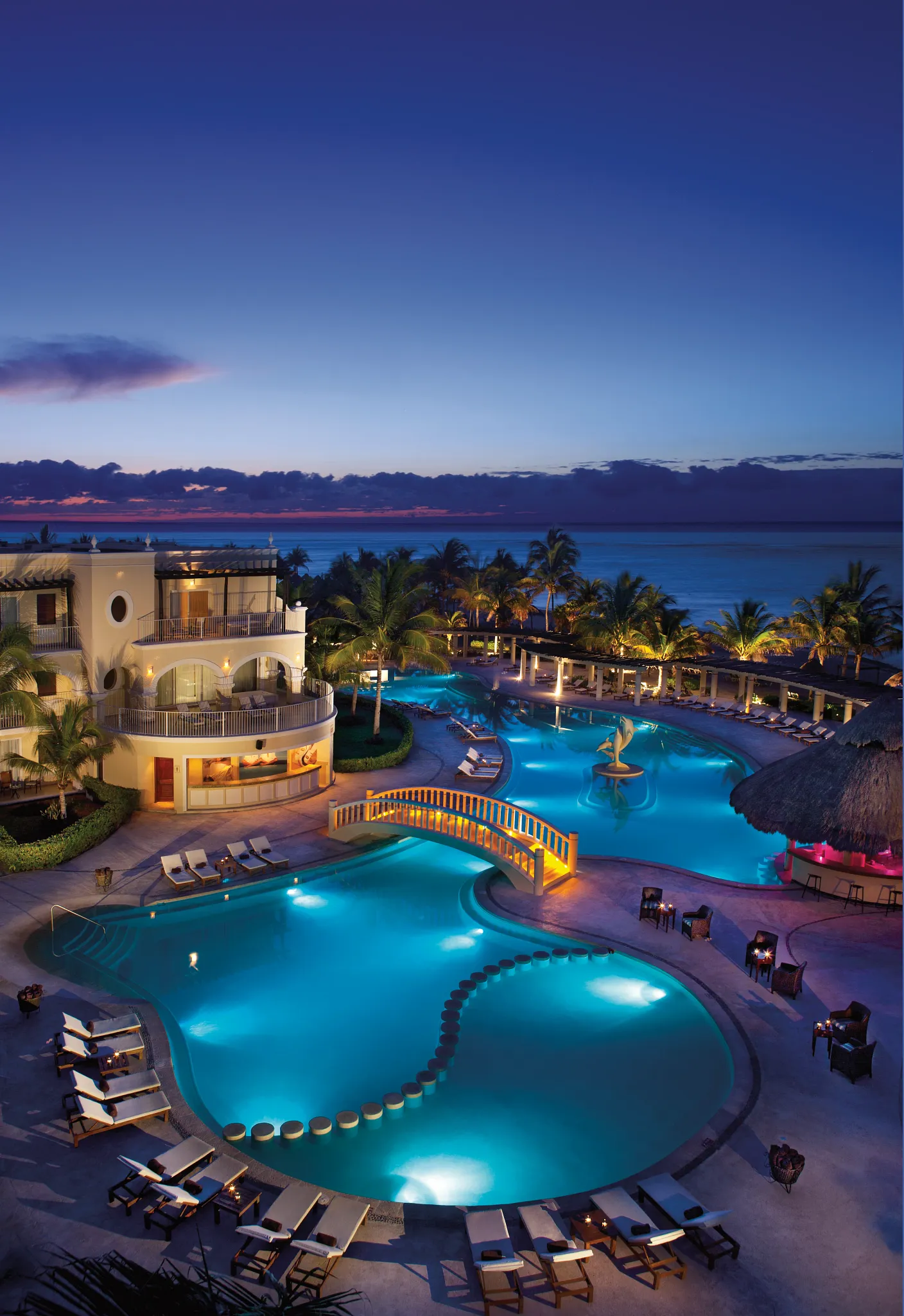 Main pool illuminated at night overlooking the Caribbean Sea at Dreams Tulum Resort & Spa.