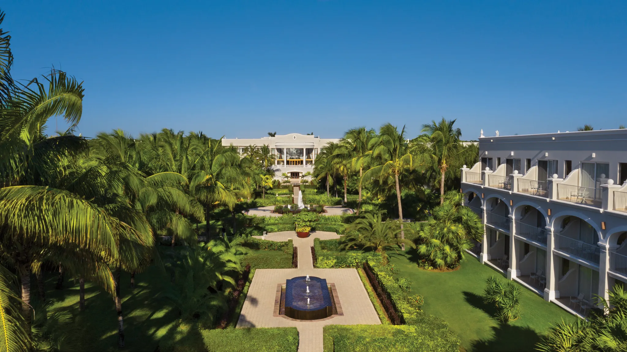 Panoramic view of lush tropical gardens and colonial-style buildings at Dreams Tulum Resort & Spa.